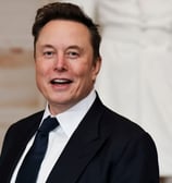 Elon Musk de terno e gravata sorrindo 