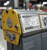 Rows of metal containers with colorful labels are stacked together, each secured by horizontal and vertical wires. The labels display vibrant designs and text in various languages.