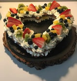 a cake with fruit on top of a wooden slice