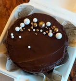 a cake in a styrofoam container with chocolate frosting