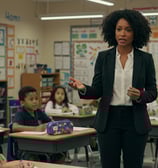 a woman in a suit and tie is standing in front of a classroom