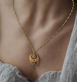 a woman wearing a necklace with a gold chain and a necklace with a heart shaped