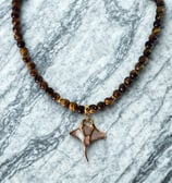 a necklace with a small bird on a marble surface