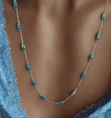 a woman wearing a blue dress and a necklace with a turquoise beaded necklace
