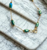 a bracelet bracelet with a gold chain and green beads