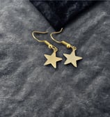 a pair of gold star earrings with a black velvet pouch