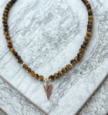a tiger eye beaded necklace with a silver arrow