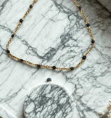 a necklace with a gold chain and a necklace with a black bead