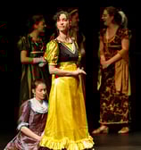 Aude Fy, en costume d'époque jaune dans une pièce de théâtre, interprétant une cantatrice