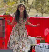 Aude Fy, chanteuse performant un spectacle sur scène avec une robe à fleurs et un béret blanc