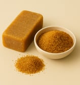 A rustic block of Colombian panela next to a bowl and small pile of golden granulated cane sugar on