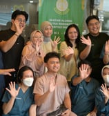 a group of people standing around a table with masks on