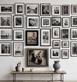 A display stand holds various art prints and posters in frames. Each print features colorful and diverse artwork, including cityscapes and famous magazine covers. A sign on top reads '$6 with frame 8x10'. The background shows leafy trees.