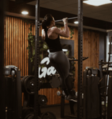 a woman doing a pull up barbell in a gym