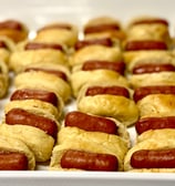 Platter full of cocktail sausages in Lil Smoky buns sitting in rows.