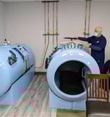 a man in a mask and a mask on a chair hyperbaric camara hyperbarica