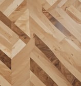 A textured wooden floor with rectangular planks arranged in a staggered pattern. The surface features natural wood grain and shading, creating a sense of depth and dimension.