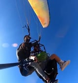 A pilot flying with a passenger, both enjoying the paraglide ride