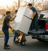 Lifting an old refrigerator into the back of a pickup truck.