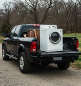 A black pickup truck hauling away an old appliance.