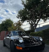 a black porsche 911r parked in front of a fence