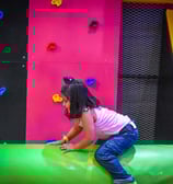a young girl is playing on a slider in a play area