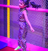 a girl in a leopard print jumpsuit and neon green shoes