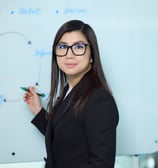 a woman in a suit and glasses is standing in front of a white board