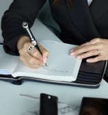 a woman in a suit writing on a notebook