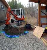 Compact spider excavator installing a test pit in confined area