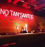 a bar with a neon sign that says no tan's on it