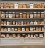 A snack bar area inside a store featuring a variety of packaged chips and snacks neatly arranged on a shelf. Above the shelf, there is a large, lit-up graphic with an artistic design, and two modern pendant lights hang from the ceiling. The word 'refresh' is prominently displayed at the top. The background includes a blue wall and a door with some posters or notices on it.