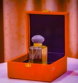 a small orange box with a perfume bottle in it