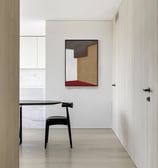 canto de uma cozinha com cadeira e mesa pretas e quadro geométrico nas cores branco, vermelho e tons