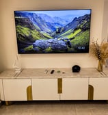 A modern and elegant living room setup featuring a wall-mounted TV, a sleek white and gold marble-to