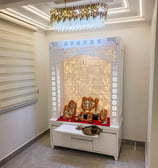 A beautifully designed home temple with intricate carvings, divine idols adorned with marigold garla