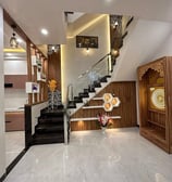 A modern staircase with wooden and glass accents, featuring elegant decor and a dedicated pooja spac