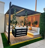 A modern outdoor lounge with a sleek pergola, LED lighting, built-in seating, and a hanging swing, c