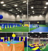 An indoor sports facility featuring several padel courts with blue playing surfaces and orange sidelines. There are players engaged in a game on one of the courts, while the others appear empty. The area is well-lit with overhead lighting and enclosed by a high ceiling and metal structure.