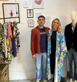a man and woman standing in front of a display of clothing