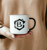 a person holding a mug with a black and white logo