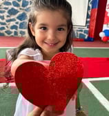 Uma aluna da educação infantil do centro educacional florescer segurando um coração de EVA