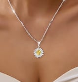 a woman wearing a white dress and a necklace with a yellow flower