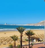 tourisme maroc Agadir Vue panoramique de la plage d'Agadir avec sa promenade bordée de palmiers et l'océan Atlantique en arri