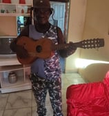 Sr. João Reis com seu violão, figura marcante da cultura quilombola de São Tomé