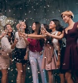 Women toasting with champagne surrounded by falling confetti on Fremont Street.