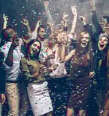 Group of friends celebrating under confetti at a Fremont Street party in Downtown Las Vegas.
