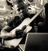 Dr. Marlon Ware sitting and playing a guitar