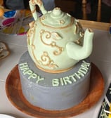 a cake with a teapot on top of a cake