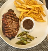Grilled steak served with French fries and smoky barbecue sauce on a stylish wooden platter
